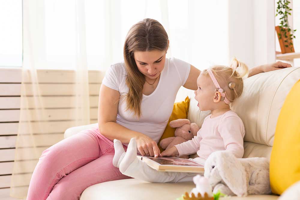 Mother reading to a child with a bone conduction device