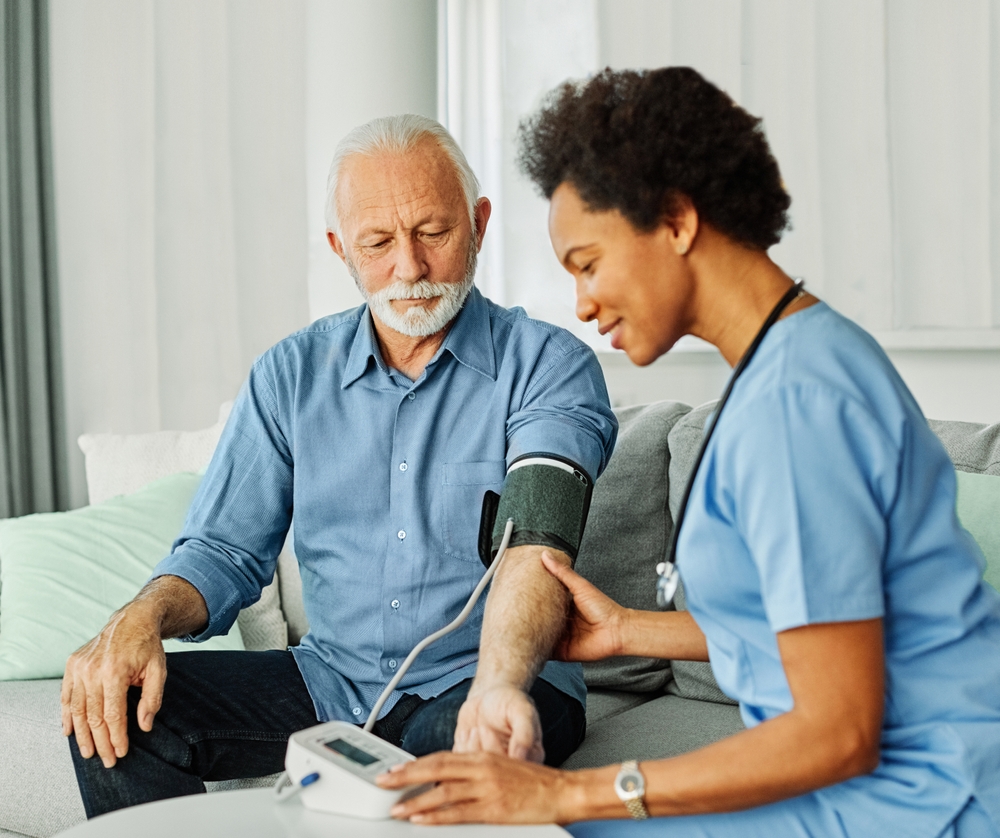 caregiver taking the blood pressure of an elderly man