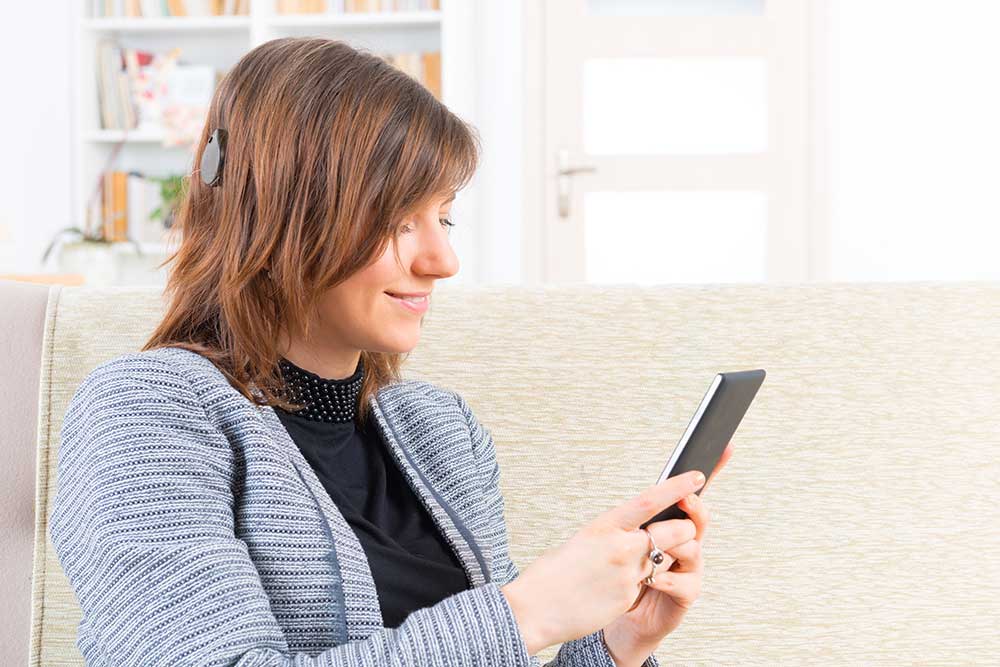 woman with cochlear device looking at phone